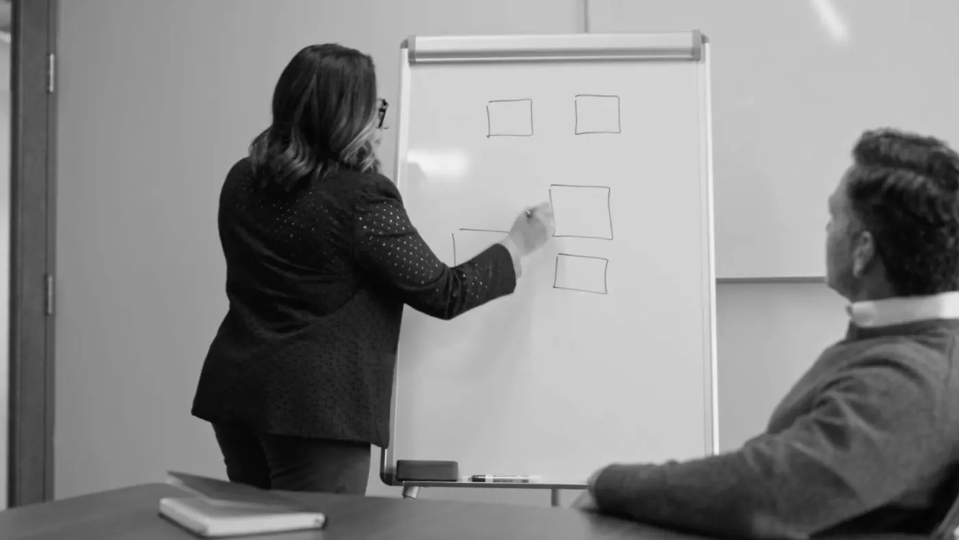 Maribel Rosario mapping a business process on a whiteboard with a business owner